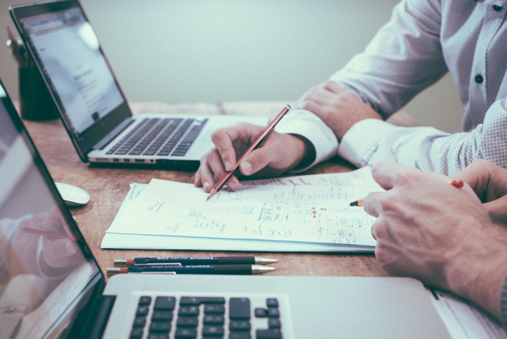 people collaborating with laptop and papers and pen